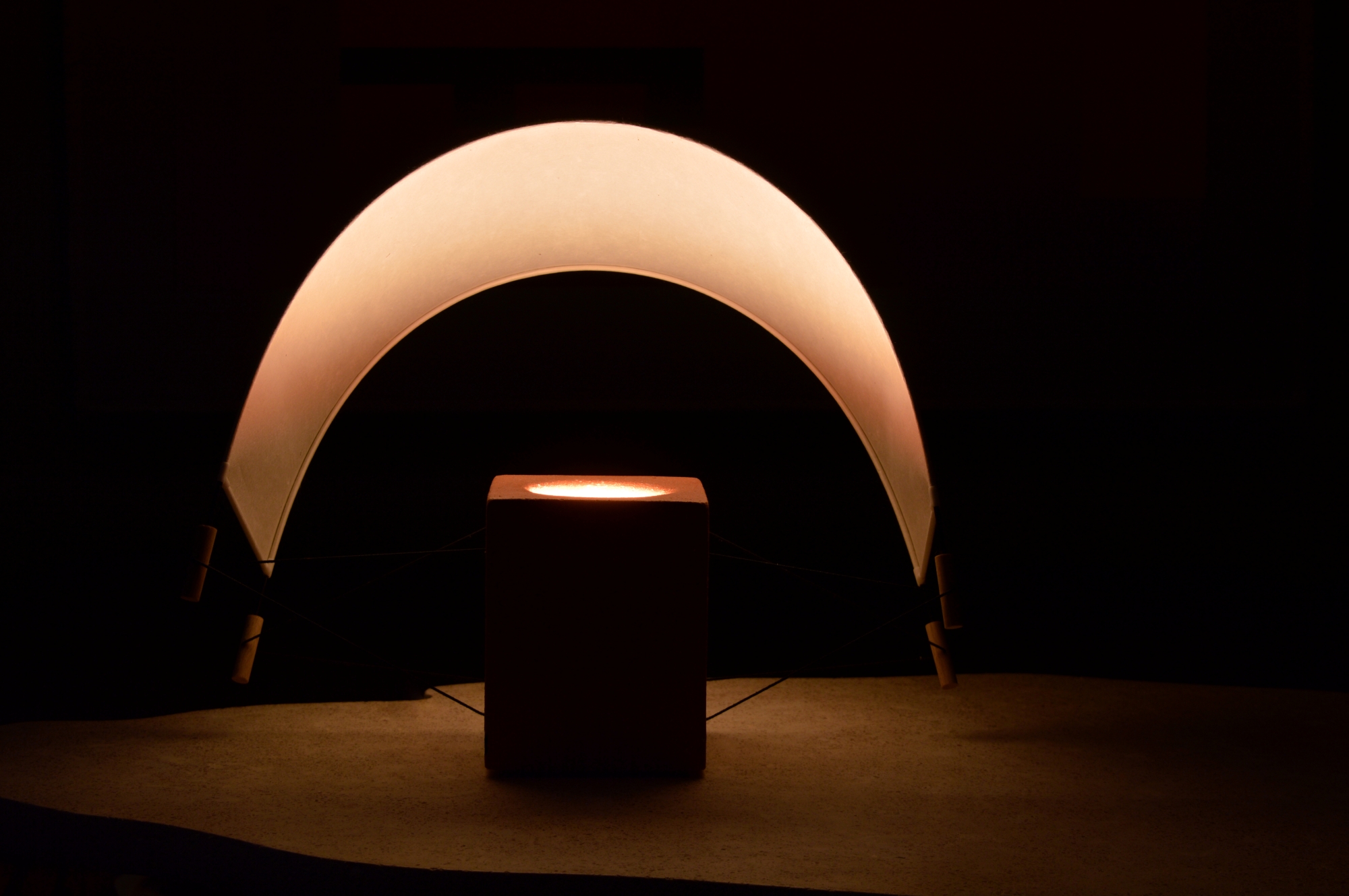 Écla Terracotta, petite lampe à poser allumée, en papier washi et terre cuite avec l'abat-jour incliné vers l'arrière.