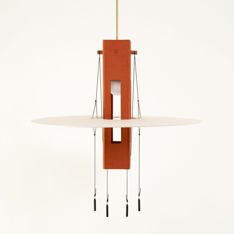 Image produit de la suspension lumineuse Nova de la Collection Aura créée par Maison Cédrat. Elle se compose d'un corps suspendu en terre cuite façonné en France autour duquel gravite un anneau en papier washi fabriqué en France.
