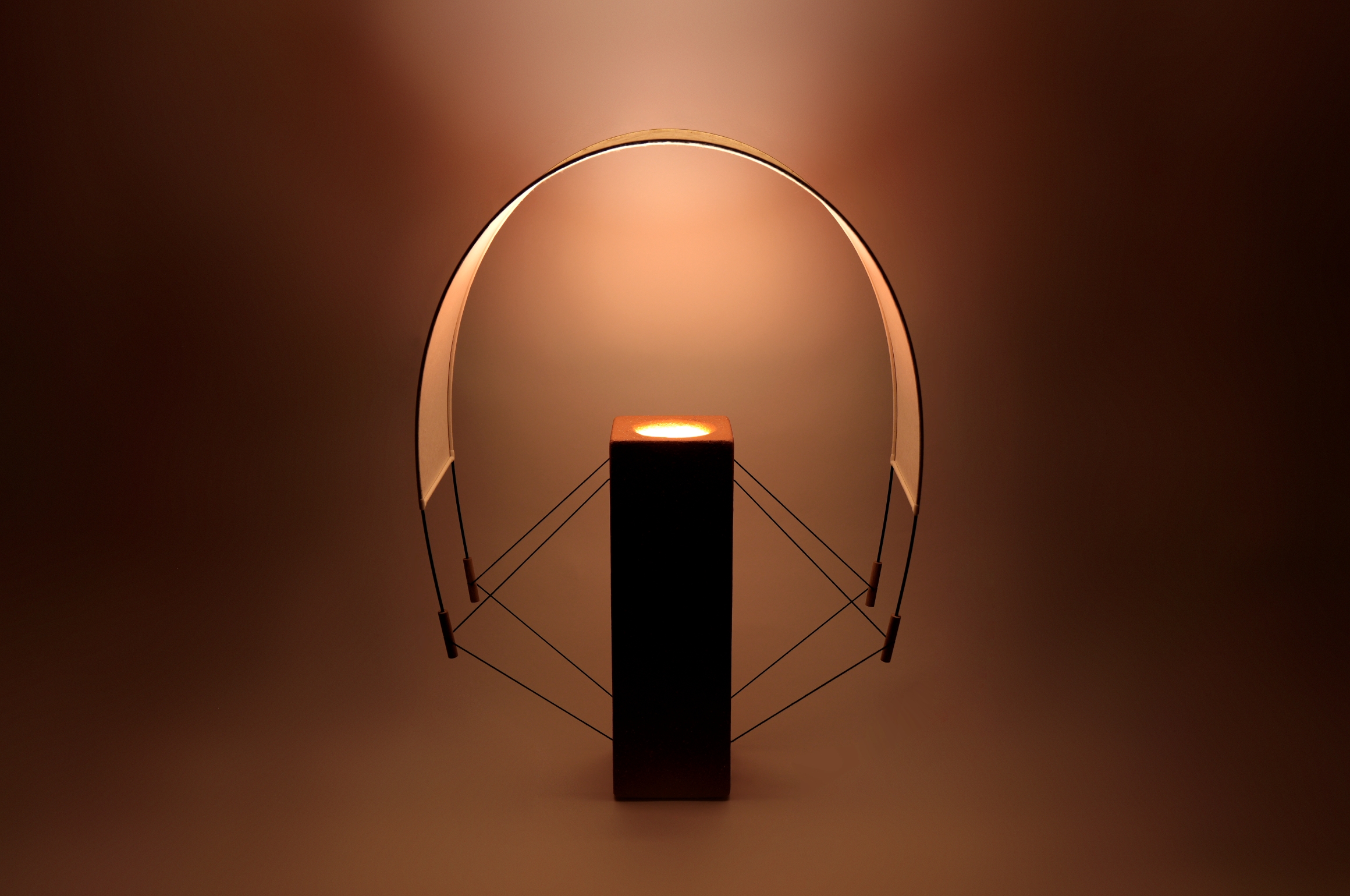 Photo Lumia lampe à poser de la Collection Aura réalisée par Maison Cédrat. Fabriqué en terre cuite et en papier japonais. En finition terre cuite, la lumière se teinte de rouges rosés et diffuse une lumière d'ambiance chaleureuse.