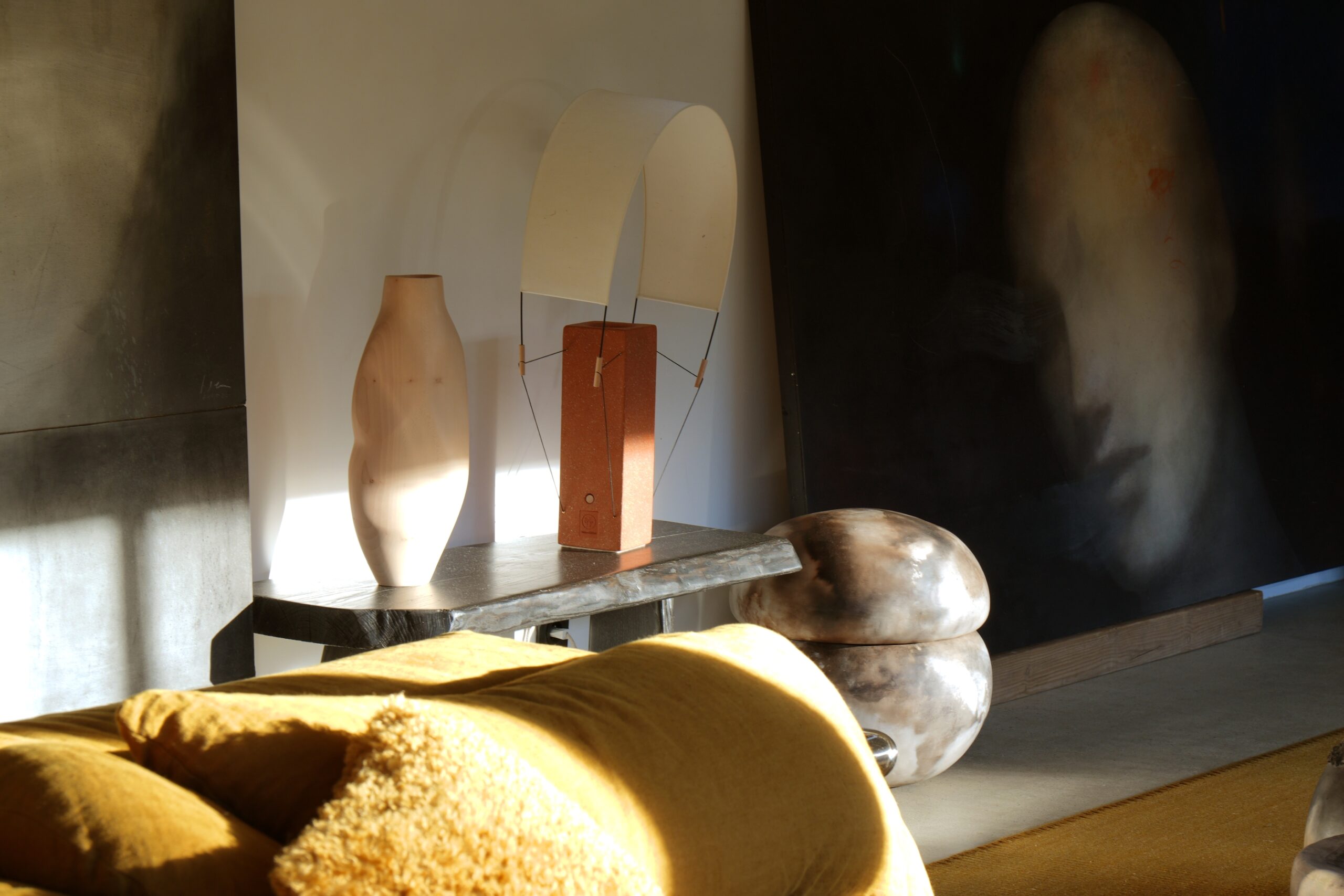 Photographie de la lampe à poser lumia en terre cuite avec un jeu d'ombres portées. Elle est entourée d'objets artisanaux design et contemporain et se marie à perfection dans se décor