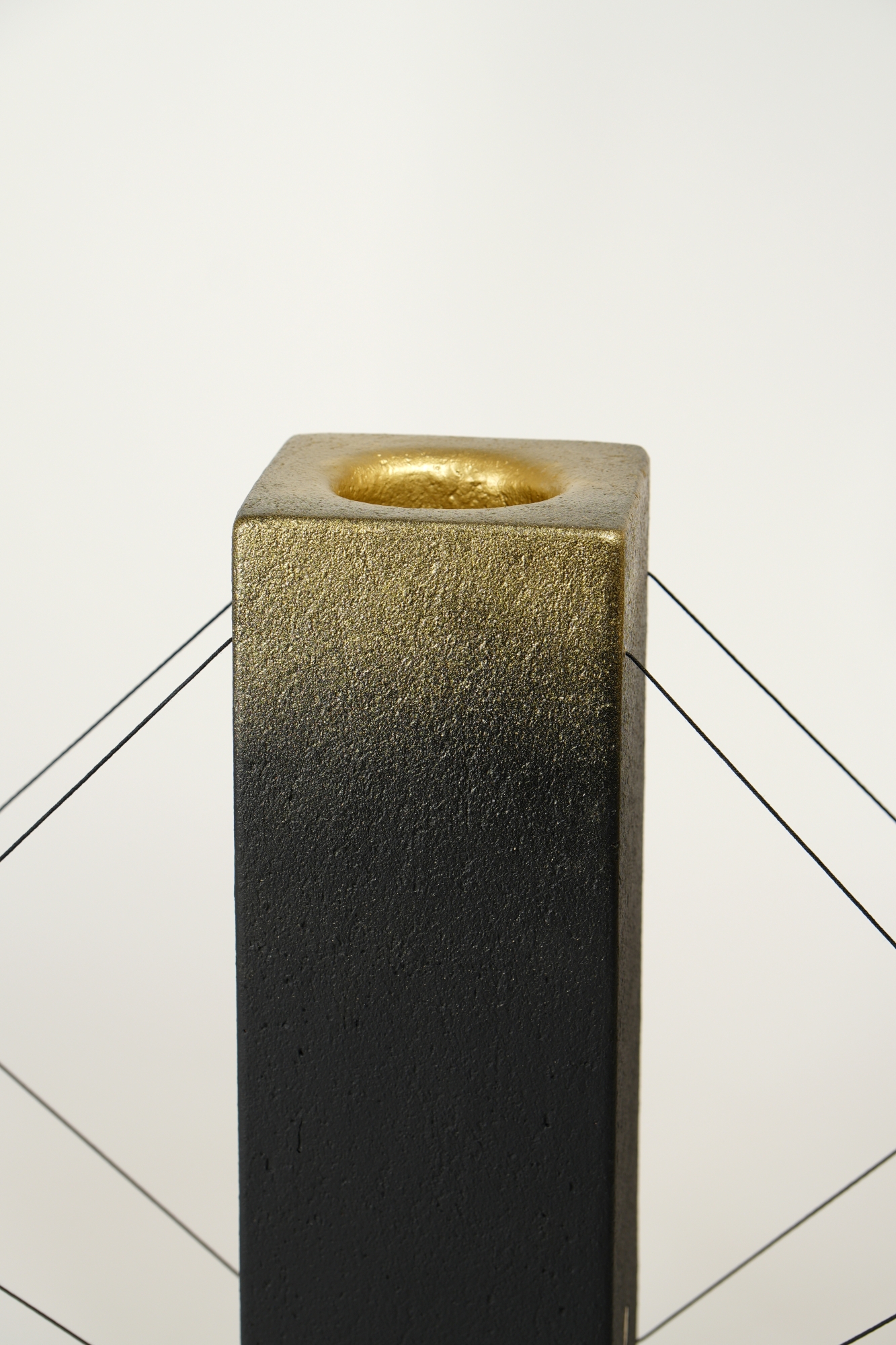 Gros plan sur la finition dorée de la lampe à poser Lumia d'Or. Réalisée en pièce unique dans le cadre d'une collaboration avec le chocolatier Thierry Papereux, cette finition fait écho aux emblématiques Palets d'Or et révèle le caractère artisanal de la création.
