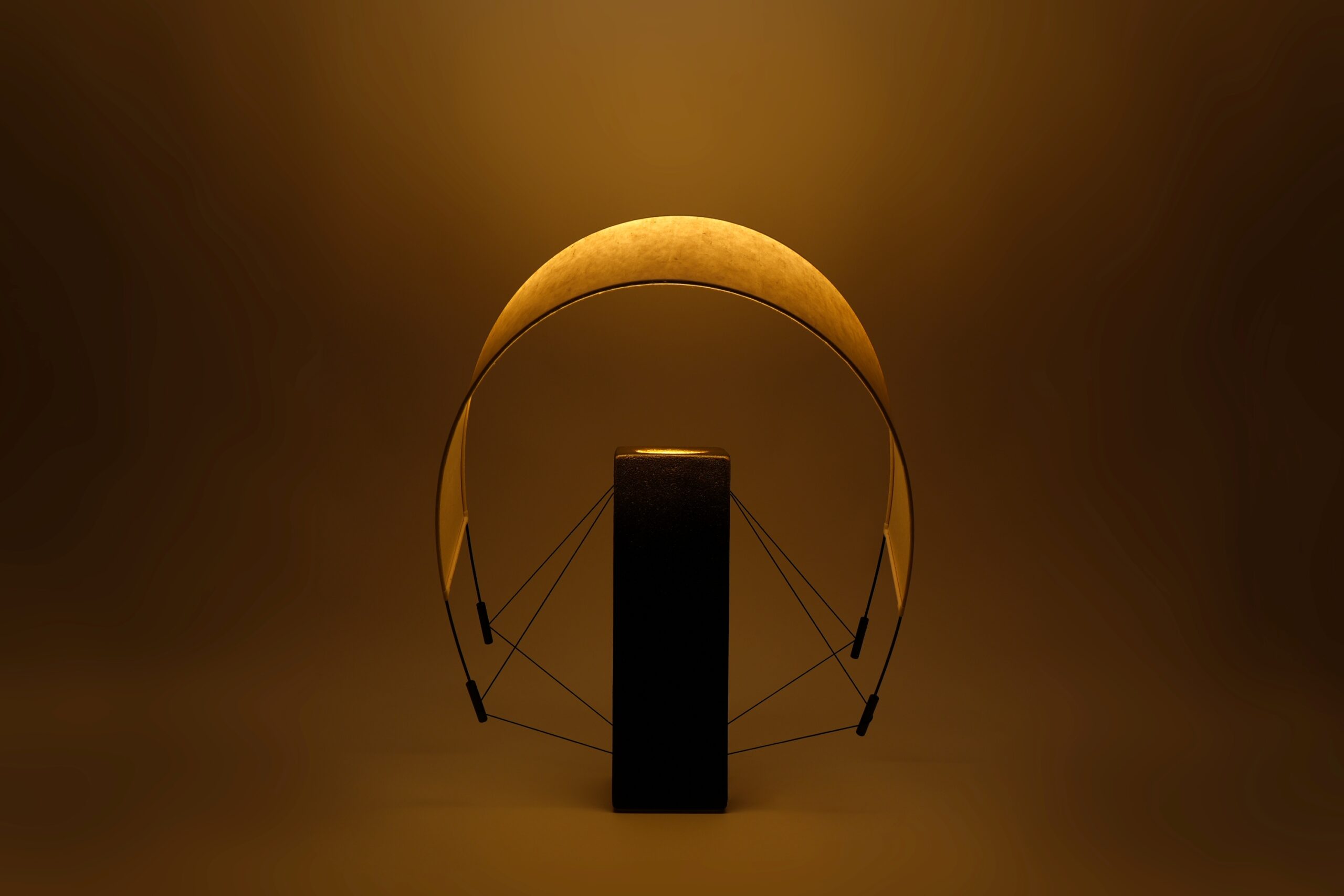 Vue de Lumia d'Or allumée avec son abat-jour orienté vers l'avant. Cette position met en valeur la diffusion de la lumière et les lignes sculpturales de cette création artisanale en terre cuite et papier washi.