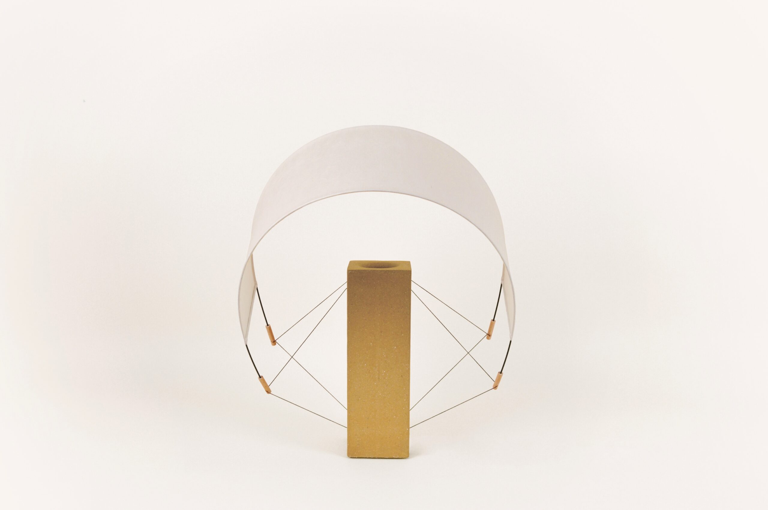 Lumia Terre Crue éteinte avec l'abat-jour incliné vers l'avant, posée sur un fond neutre, lampe à poser design de la collection Aura par Maison Cédrat