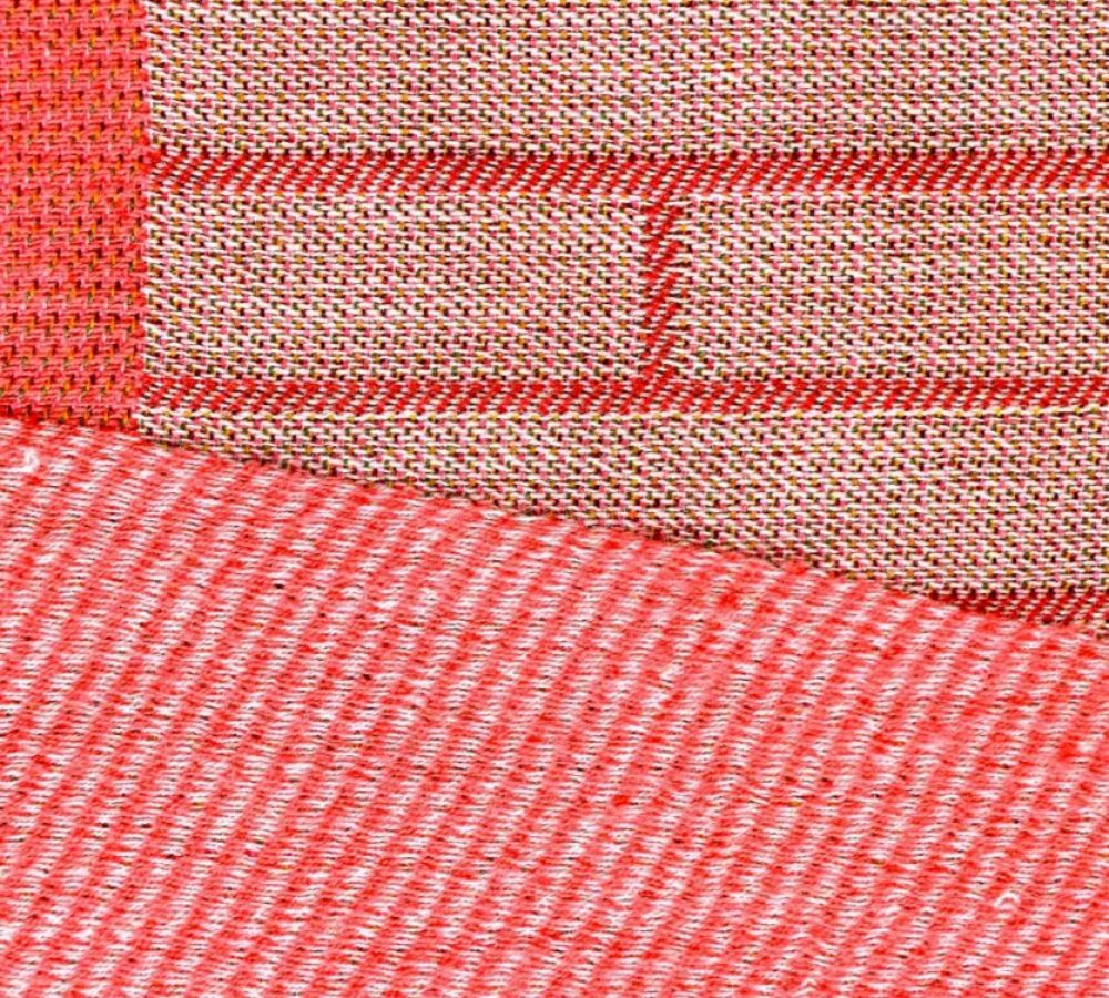 Détails du tissage jacquard du plais en laine Étreinte de la Collection Aura. Formes géométriques rayées rouge rosé.