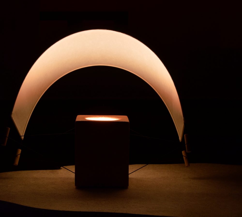 Écla Terracotta, petite lampe à poser allumée, en papier washi et terre cuite avec l'abat-jour incliné vers l'arrière.