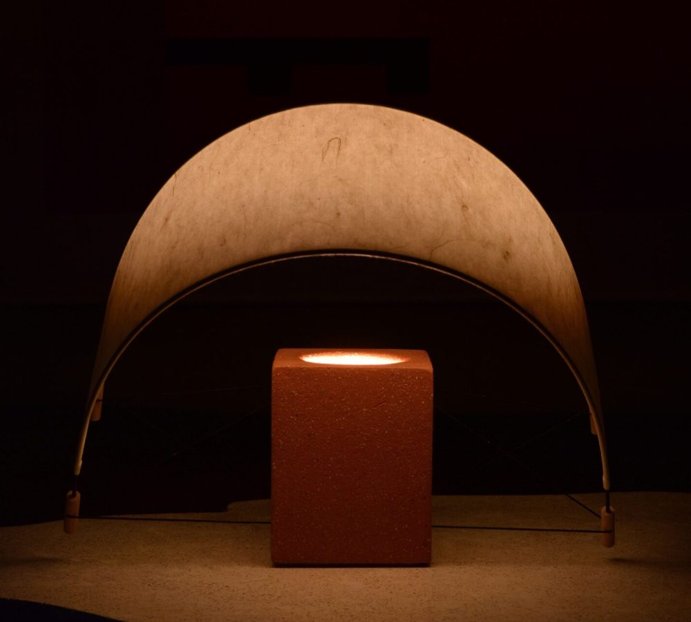 Écla Terracotta, petite lampe à poser allumée, en papier washi et terre cuite avec l'abat-jour incliné vers l'avant.