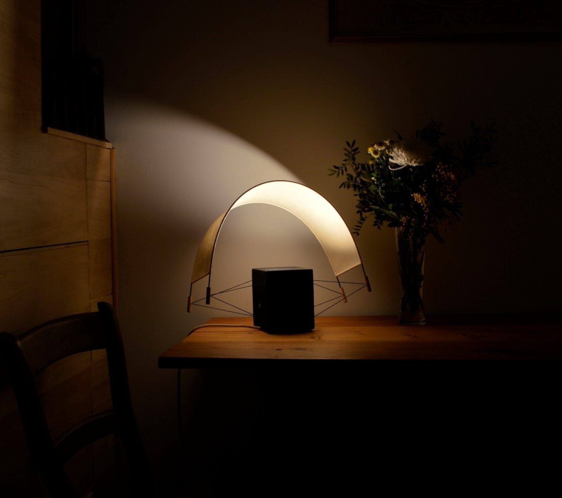 Photographie de la lampe à poser Ecla vue de profil dans un chalet en bois. Allumée elle diffuse une atmosphère réconfortante et chaleureuse.