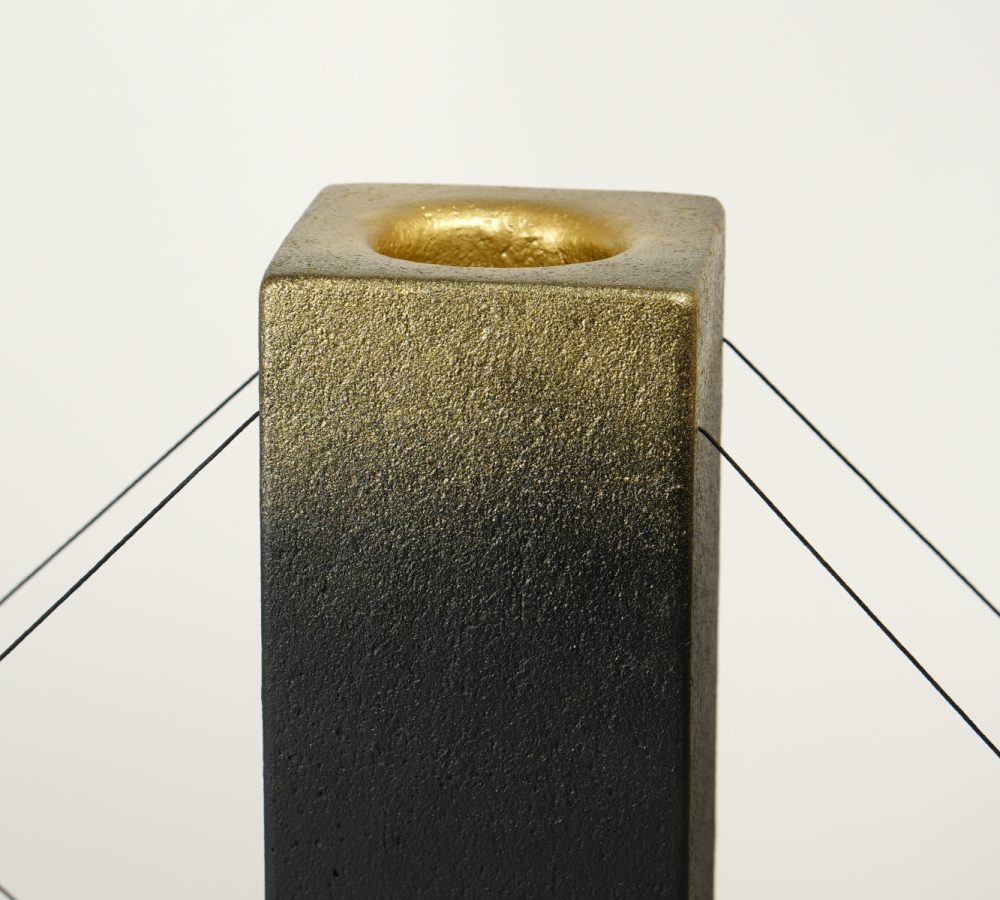 Gros plan sur la finition dorée de la lampe à poser Lumia d'Or. Réalisée en pièce unique dans le cadre d'une collaboration avec le chocolatier Thierry Papereux, cette finition fait écho aux emblématiques Palets d'Or et révèle le caractère artisanal de la création.