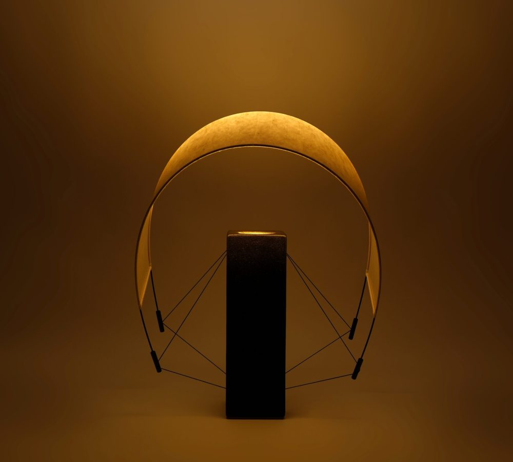 Vue de Lumia d'Or allumée avec son abat-jour orienté vers l'avant. Cette position met en valeur la diffusion de la lumière et les lignes sculpturales de cette création artisanale en terre cuite et papier washi.