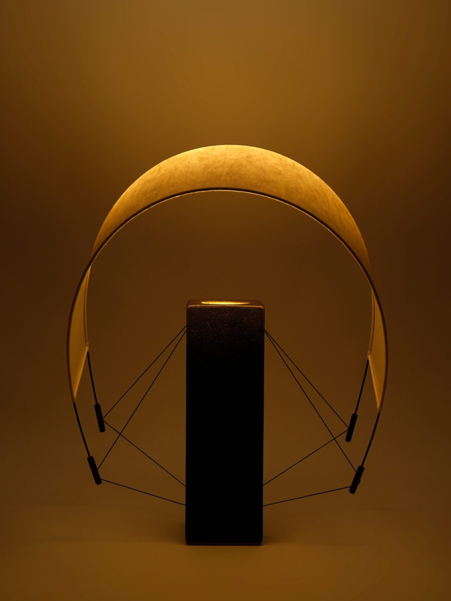 Vue de Lumia d'Or allumée avec son abat-jour orienté vers l'avant. Cette position met en valeur la diffusion de la lumière et les lignes sculpturales de cette création artisanale en terre cuite et papier washi.