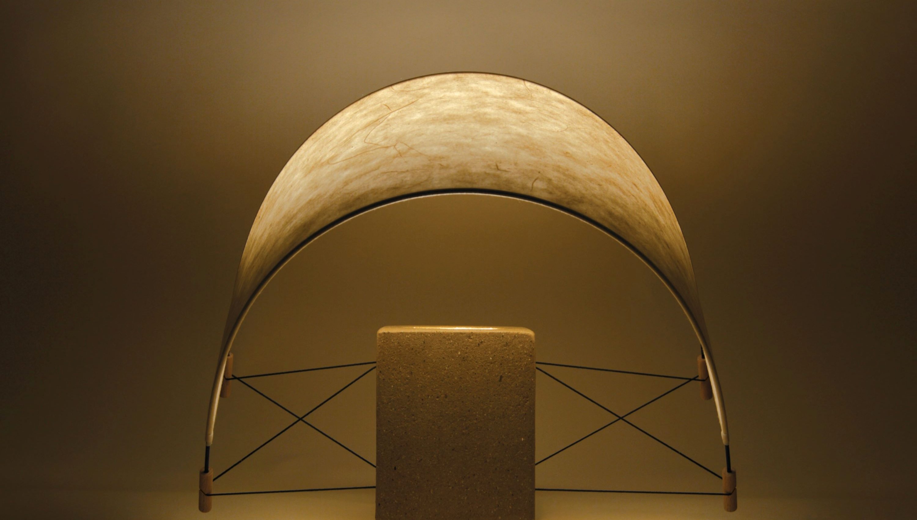 Écla Terre Crue, lampe à poser allumée en papier washi er terre crue avec l'abat-jour incliné vers l'avant.