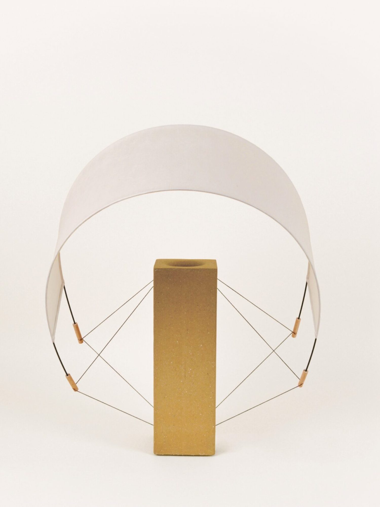 Lumia Terre Crue éteinte avec l'abat-jour incliné vers l'avant, posée sur un fond neutre, lampe à poser design de la collection Aura par Maison Cédrat