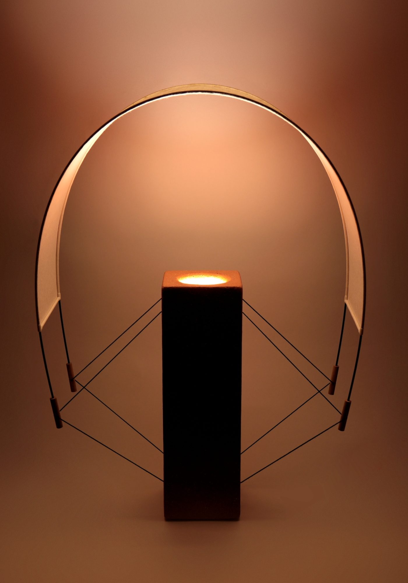 Photo Lumia lampe à poser de la Collection Aura réalisée par Maison Cédrat. Fabriqué en terre cuite et en papier japonais. En finition terre cuite, la lumière se teinte de rouges rosés et diffuse une lumière d'ambiance chaleureuse.